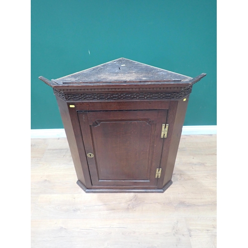 335 - A Georgian oak hanging Corner Cupboard with fretwork frieze above fielded panel door 3ft H x 2ft 9in... 