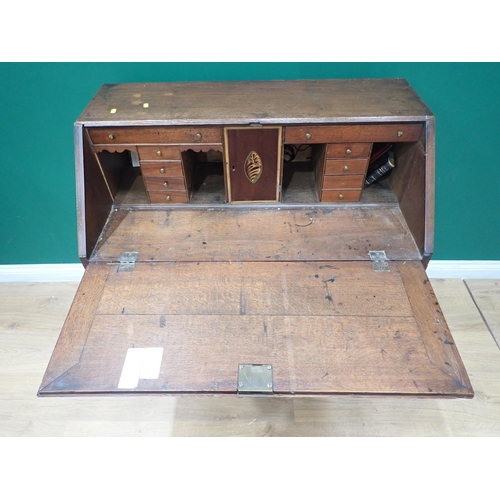 348 - A 19th Century oak bureau with sloping front enclosing a fitted interior above two short and three l... 