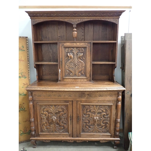 817 - A carved oak Sideboard fitted griffin carved cupboard above base fitted pair of green man carved cup... 