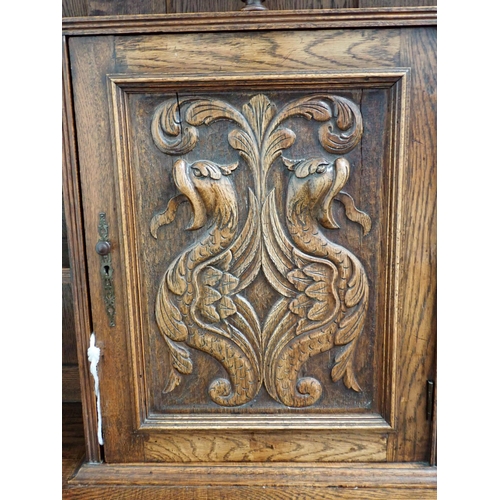 817 - A carved oak Sideboard fitted griffin carved cupboard above base fitted pair of green man carved cup... 