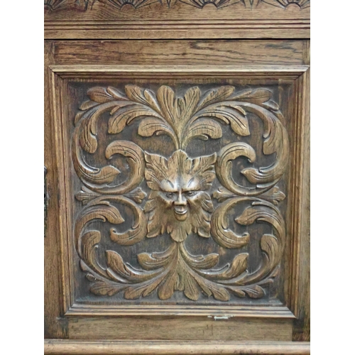 817 - A carved oak Sideboard fitted griffin carved cupboard above base fitted pair of green man carved cup... 