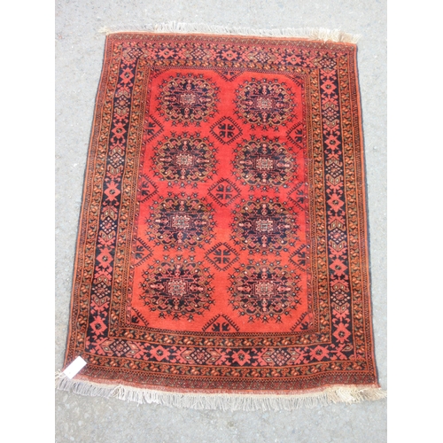 10 - A bordered Afghan Rug with eight stylised guls on a red ground, 5ft x 3ft 5in