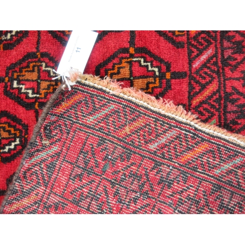 11 - A bordered Turcoman type Rug with central field of conjoined guls on a red ground, 4ft 7in x 3ft 9in