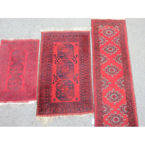 12 - A bordered Afghan Runner with five guls on a red ground, 6ft 4in x 1ft 10in, and two small Rugs with... 