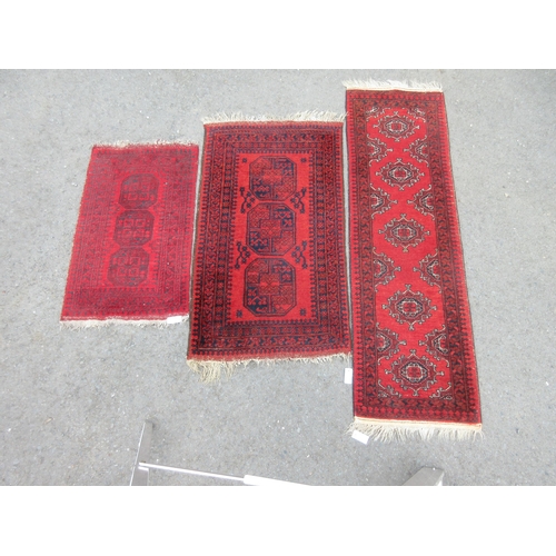 12 - A bordered Afghan Runner with five guls on a red ground, 6ft 4in x 1ft 10in, and two small Rugs with... 