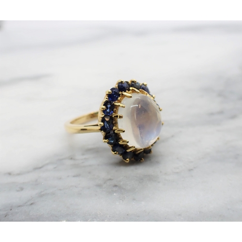 163 - A Moonstone and sapphire Cluster Ring claw-set oval moonstone cabochon within a frame of cushion-cut... 