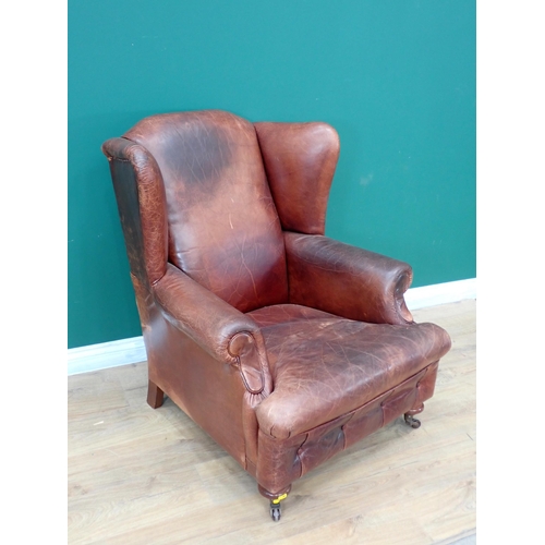 292 - A brown leather wingback Armchair on turned supports and casters