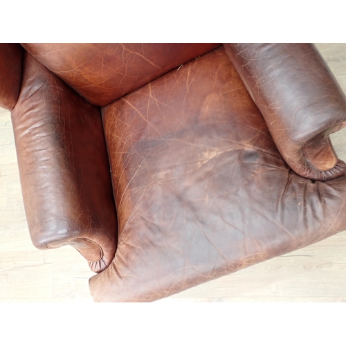 292 - A brown leather wingback Armchair on turned supports and casters