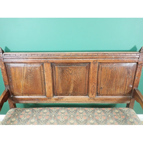 394A - A 17th Century oak Settle with fielded three panel back and cushioned supports mounted on ball turne... 