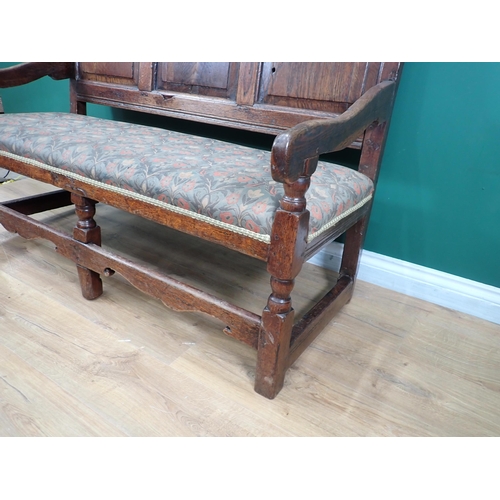 394A - A 17th Century oak Settle with fielded three panel back and cushioned supports mounted on ball turne... 