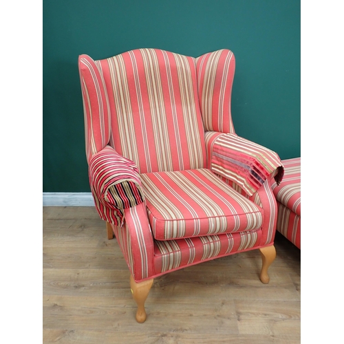 702 - An upholstered wingback Armchair with cabriole supports and a Footstool with matching upholstery