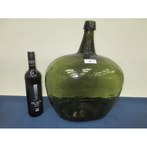 93 - An unusually large 19th Century olive green glass Wine Bottle, 17in high and 12in wide