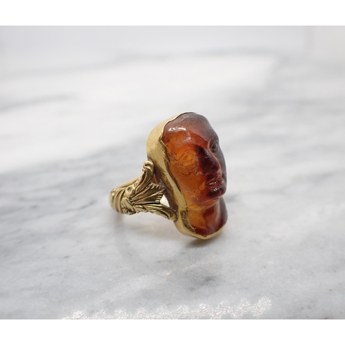 162 - A 19th Century gold Ring with embossed shank set carved mask, tests as hessonite garnet, ring size I