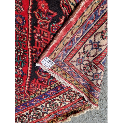 4 - An Iranian bordered Rug with stylised floral designs on a red ground, 10ft 4in x 6ft 9in