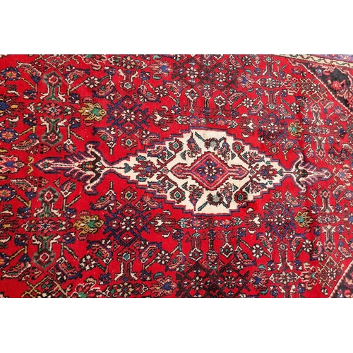 4 - An Iranian bordered Rug with stylised floral designs on a red ground, 10ft 4in x 6ft 9in