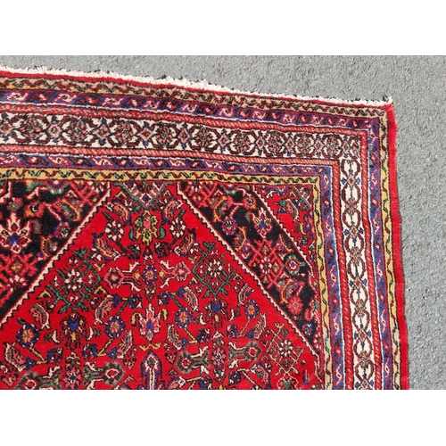 4 - An Iranian bordered Rug with stylised floral designs on a red ground, 10ft 4in x 6ft 9in