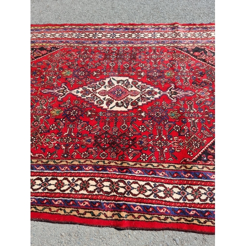 4 - An Iranian bordered Rug with stylised floral designs on a red ground, 10ft 4in x 6ft 9in