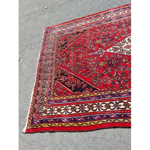 4 - An Iranian bordered Rug with stylised floral designs on a red ground, 10ft 4in x 6ft 9in