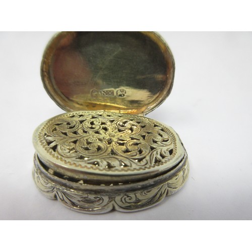 130 - A Victorian silver shaped oval Vinaigrette with floral and scroll engraving, scroll pierced grille, ... 