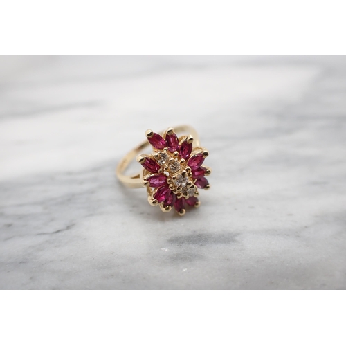 158 - A Diamond and Ruby Cluster Ring claw-set a row of five brilliant-cut diamonds within a frame of twel... 