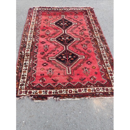 443 - A red ground Rug with three dark blue connecting lozenges within floral border 8ft 6in L x 6ft W