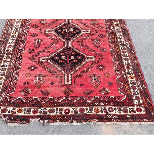 443 - A red ground Rug with three dark blue connecting lozenges within floral border 8ft 6in L x 6ft W