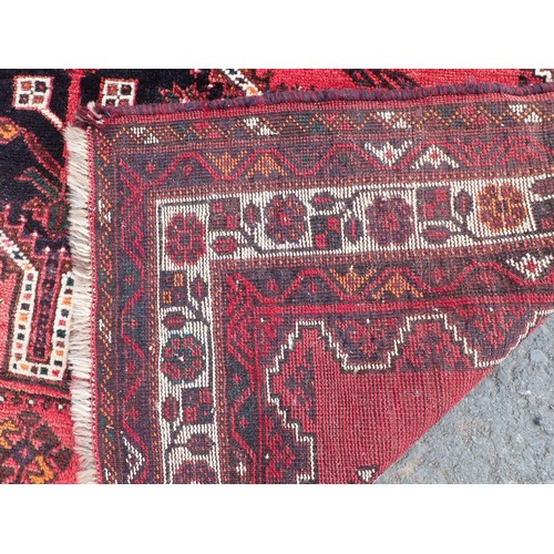 443 - A red ground Rug with three dark blue connecting lozenges within floral border 8ft 6in L x 6ft W