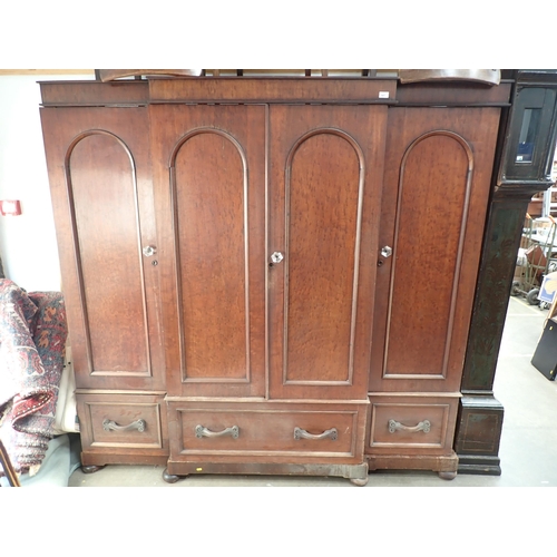 447 - A Victorian mahogany breakfront Wardrobe with arched panelled doors, fitted drawers below on bun sup... 