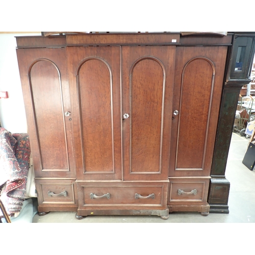 447 - A Victorian mahogany breakfront Wardrobe with arched panelled doors, fitted drawers below on bun sup... 