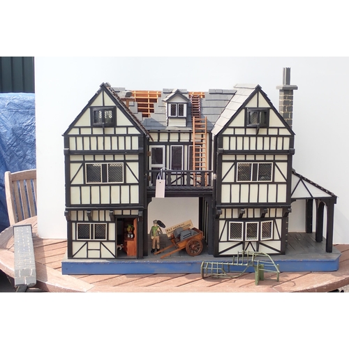 768 - A scratch built model of a timber framed black and white house, the roof made with areas of slating ... 