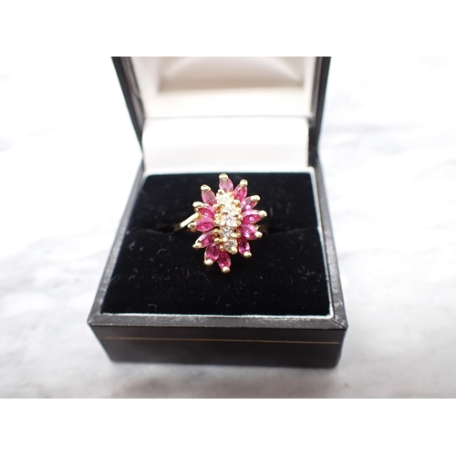 196 - A Diamond and Ruby Cluster Ring claw-set a row of five brilliant-cut diamonds within a frame of twel... 