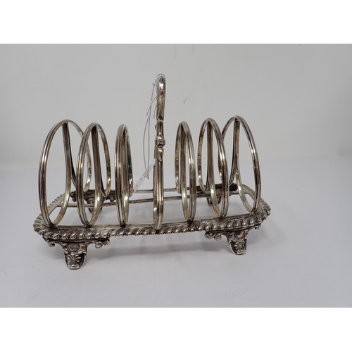 102 - A William IV silver seven bar Toastrack with central handle on ornate scroll feet, London 1835, make... 