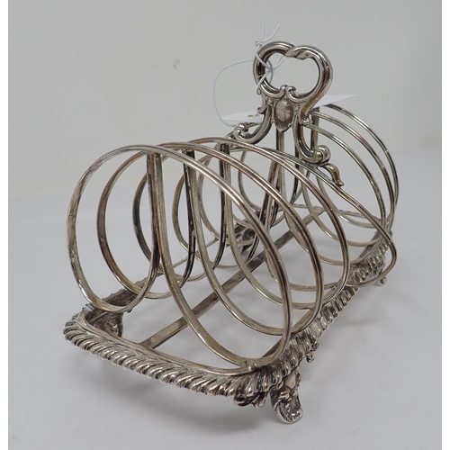 102 - A William IV silver seven bar Toastrack with central handle on ornate scroll feet, London 1835, make... 