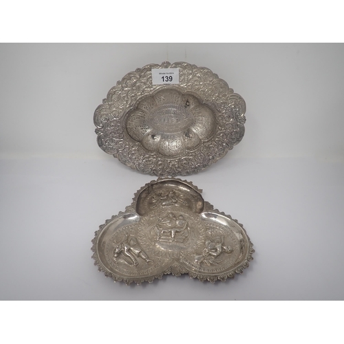 139 - An Indian silver trefoil shape Dish embossed figures, and a white metal oval Bowl engraved figures a... 