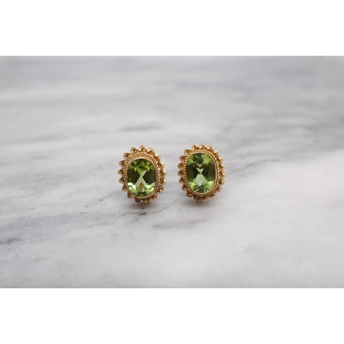 171 - A pair of Peridot Ear Studs each millegrain-set oval-cut stone in rope twist frame in 9ct gold