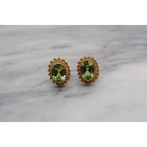 171 - A pair of Peridot Ear Studs each millegrain-set oval-cut stone in rope twist frame in 9ct gold