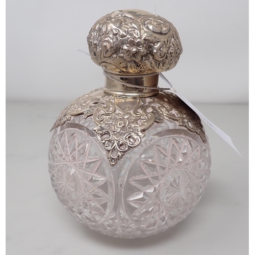 79 - An Edward VII silver lidded and mounted large cut glass Scent Bottle with floral and scroll embossin... 