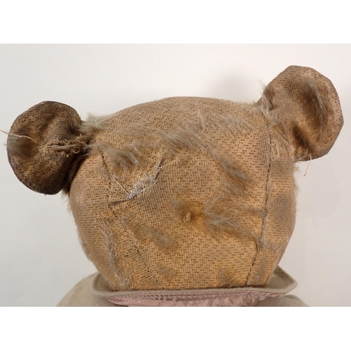 66 - An old Teddy Bear wearing a beige Coat, 21in, pads repaired and worn