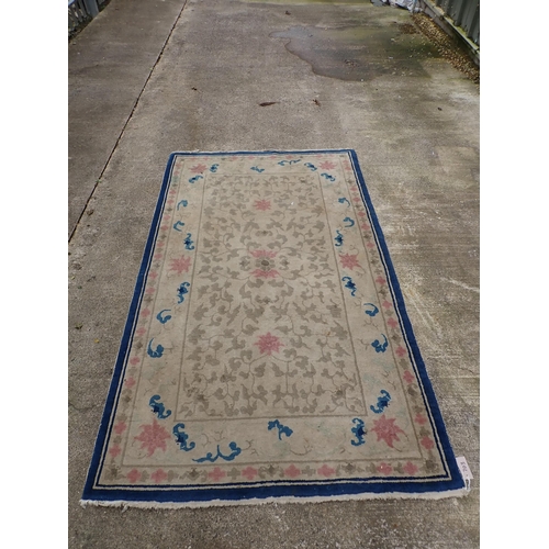 703 - A small Chinese style Rug with floral design on beige ground with blue border 7ft 10in L x 4ft