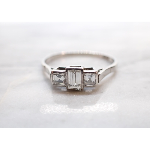 240 - A Diamond three stone Ring millegrain-set graduated step-cut stones in platinum, ring size W