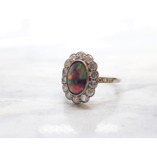 250 - A Black Opal and Diamond Cluster Ring millegrain-set oval opal within a frame of brilliant-cut diamo... 