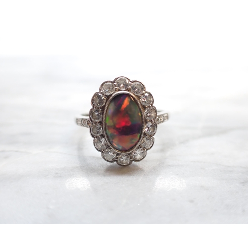 250 - A Black Opal and Diamond Cluster Ring millegrain-set oval opal within a frame of brilliant-cut diamo... 