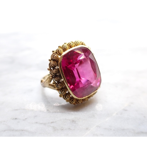 251 - A synthetic Ruby Ring millegrain-set large cushion-cut stone in cannetille frame, stamped 585, ring ... 