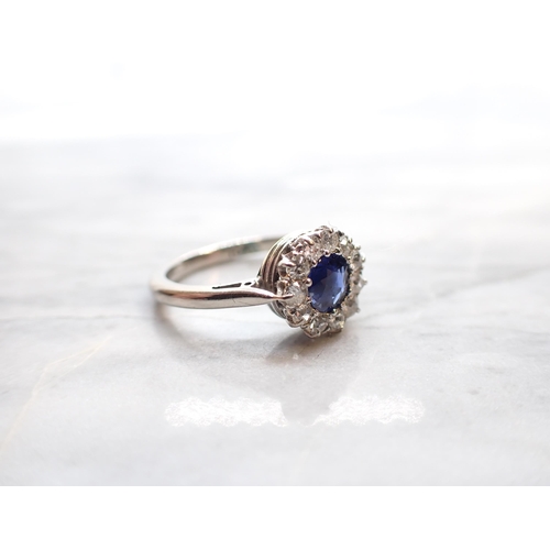 282 - A Sapphire and Diamond Cluster Ring claw-set round sapphire within frame of eleven old-cut diamonds ... 