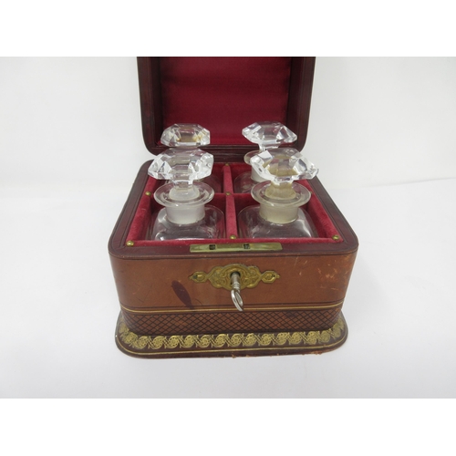 348 - A set of four square glass Perfume Bottles and Stoppers in leather case having gilt tooled decoratio... 