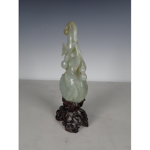 405 - An Oriental carved jade lidded Bottle vase with leafage and fruit decoration, on a carved hardwood s... 