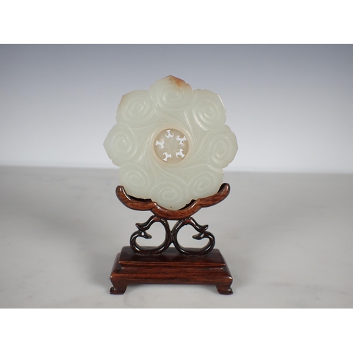 412 - A Chinese celadon Jade Bi Disk carved flower head with geometric carved centre section on hardwood s... 