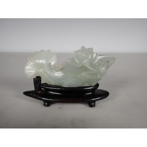 413 - A Chinese celadon Jade carved Fish with lily pad and flower to one side, small chips, on hardwood st... 