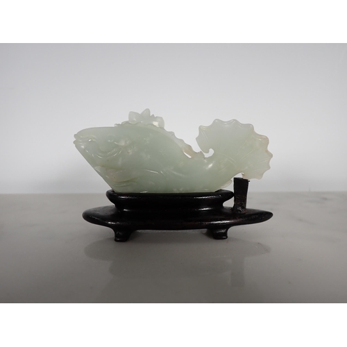 413 - A Chinese celadon Jade carved Fish with lily pad and flower to one side, small chips, on hardwood st... 