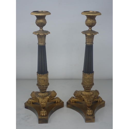 478 - A pair of French Empire Candlesticks in ormolu and bronze, with classical mouldings, plain bronze fl... 